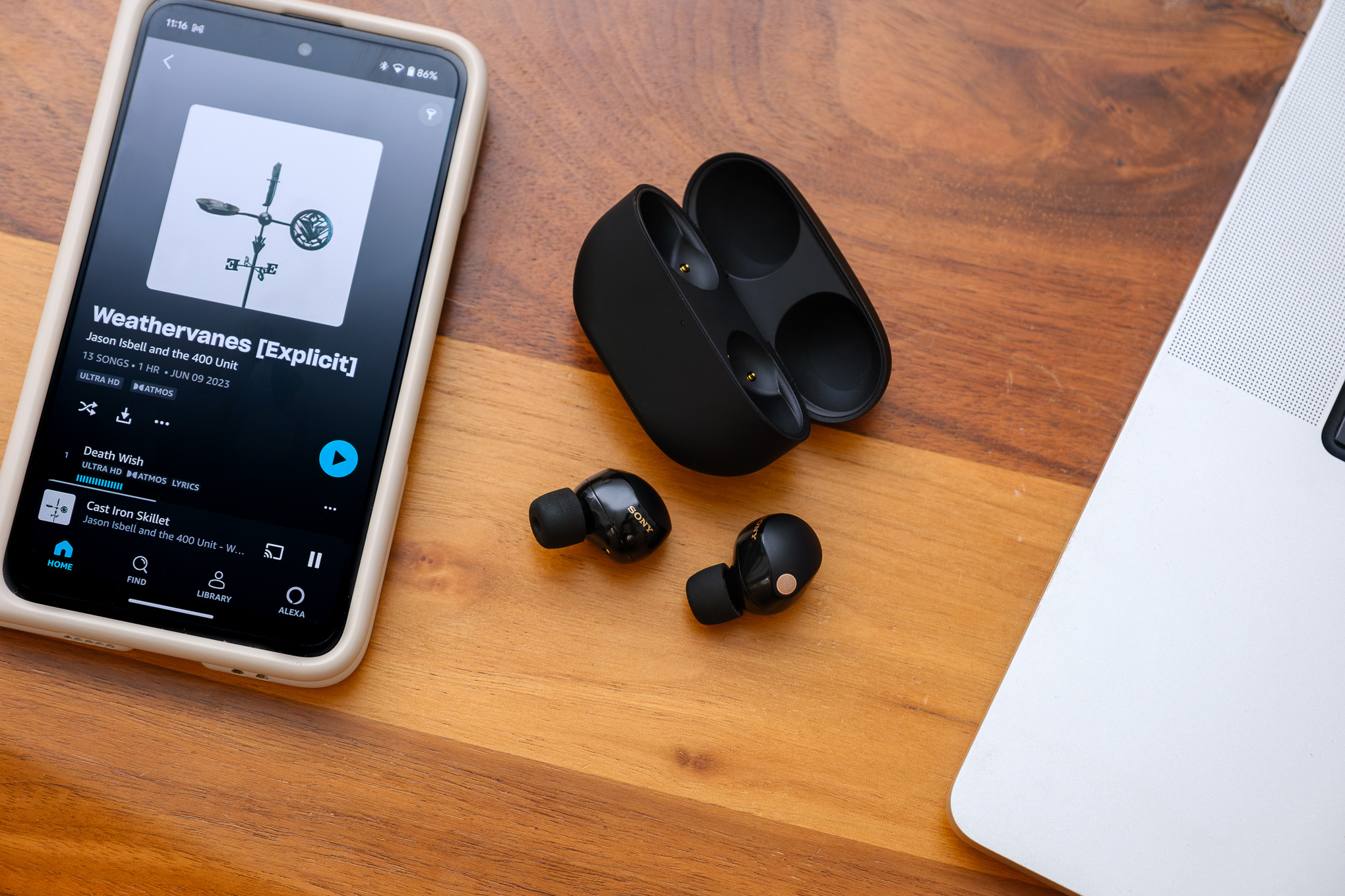 Sony WF-1000XM5 earbuds placed on a table with a smartphone