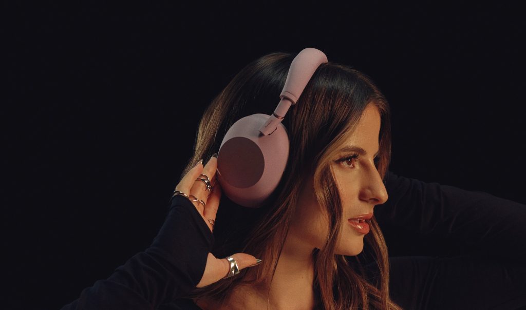 Person wearing Sony WH-1000XM6 Sand Pink headphones comfortably in a cafe
