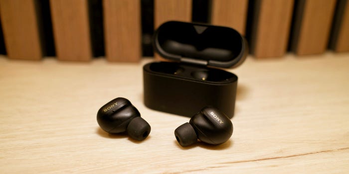 Sony WF-1000XM6 earbuds in a stylish brown leather case on a wooden table